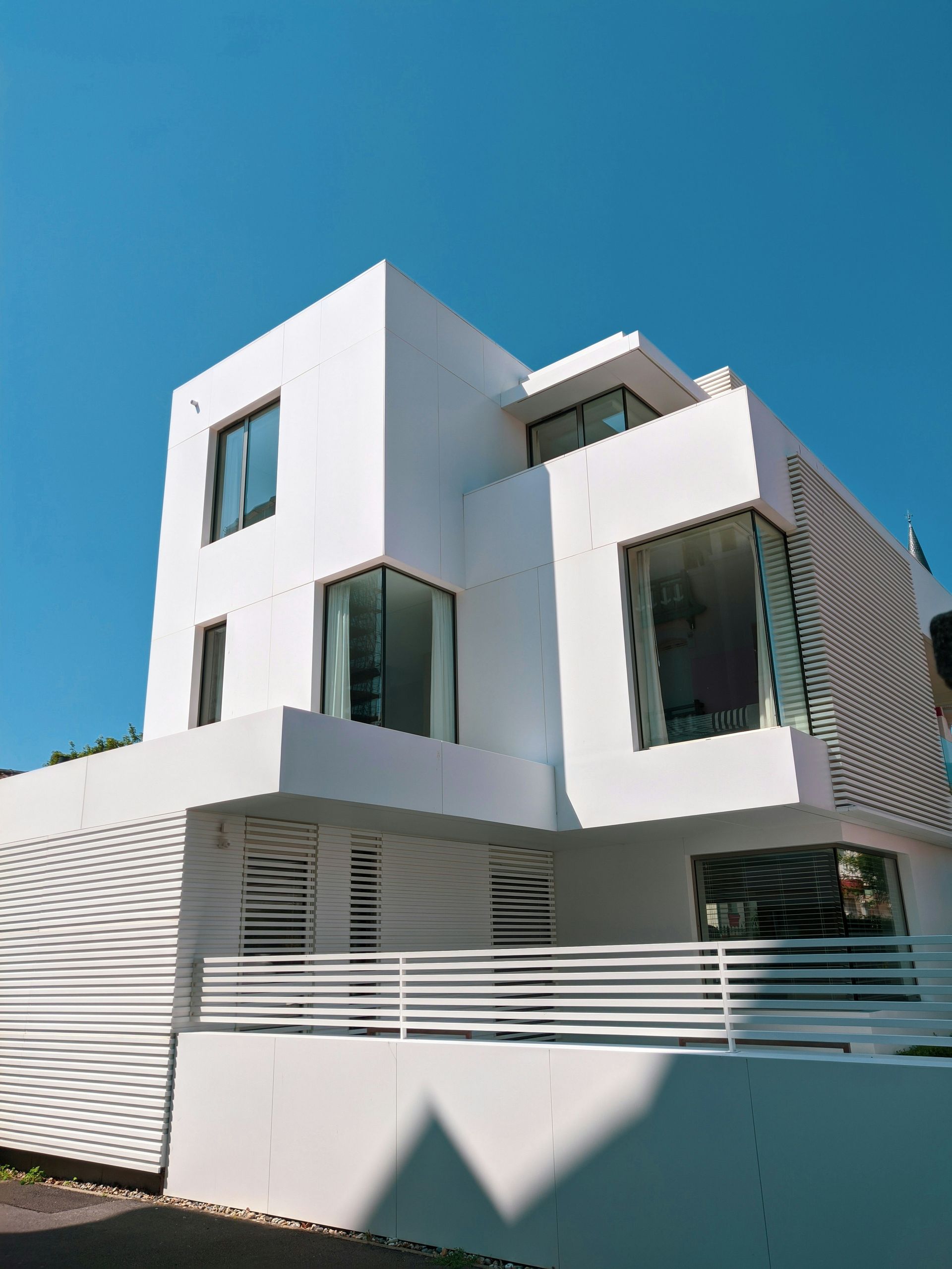 Modern white building with large windows and a curved facade under a clear blue sky