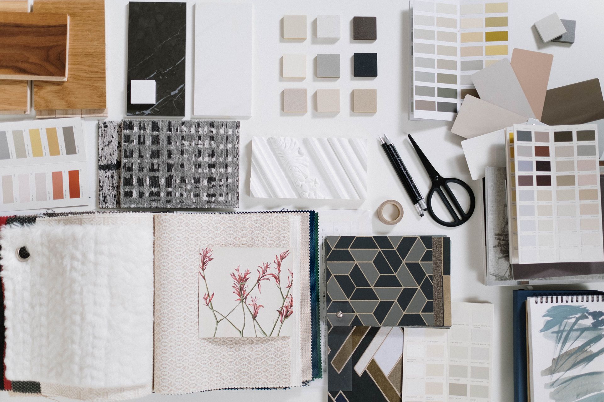 Overhead view of a design workspace with color swatches, fabric samples, notebooks, and scissors