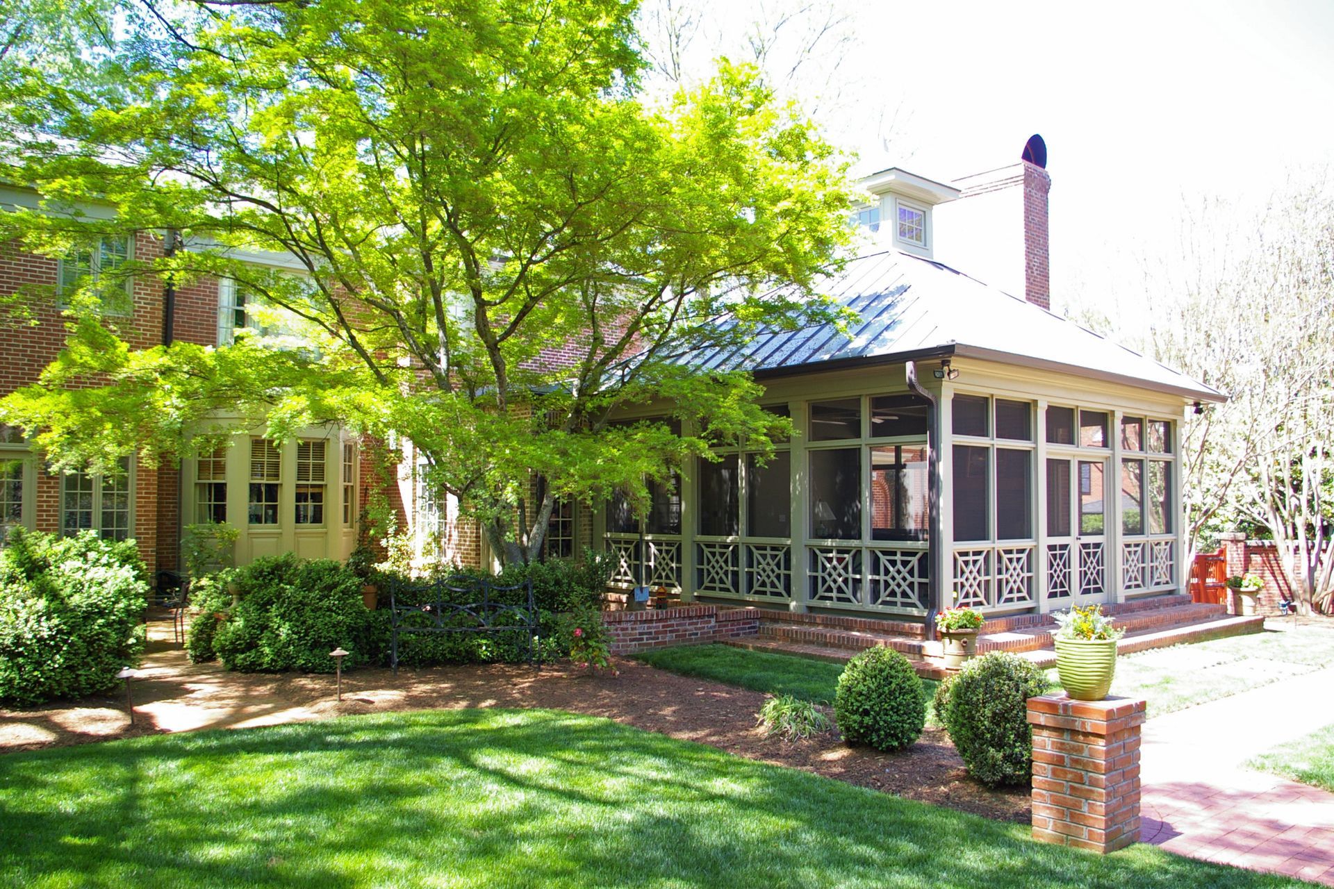 A house with a screened in porch and a large lawn in front of it.