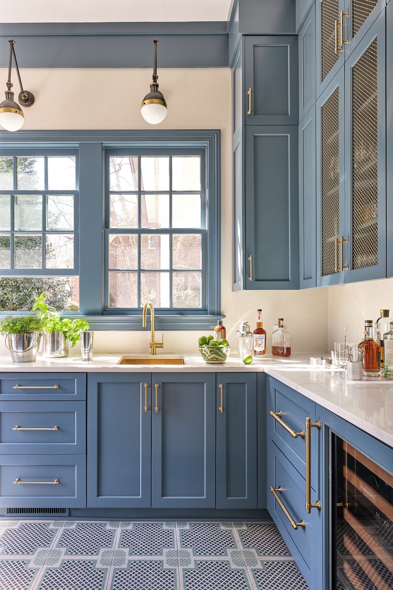 Blue kitchen with gold fixtures, white countertops, and large window over the sink