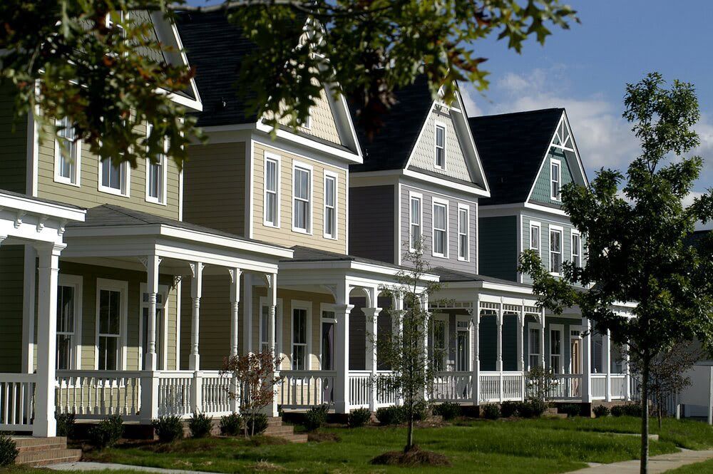 A row of houses with porches are lined up in a residential area