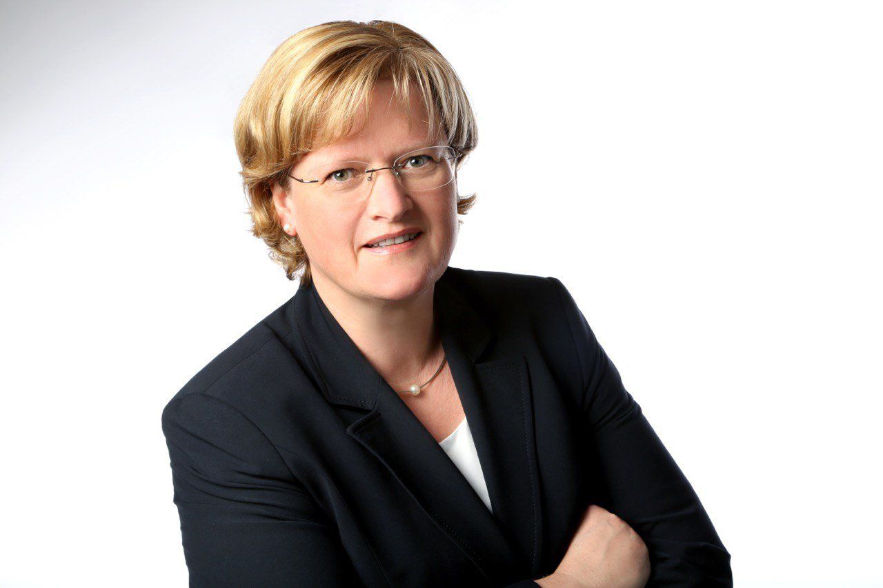 Eine Frau mit Brille und schwarzer Jacke mit verschränkten Armen