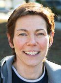 Eine Nahaufnahme des Gesichts einer Frau, die in die Kamera lächelt.