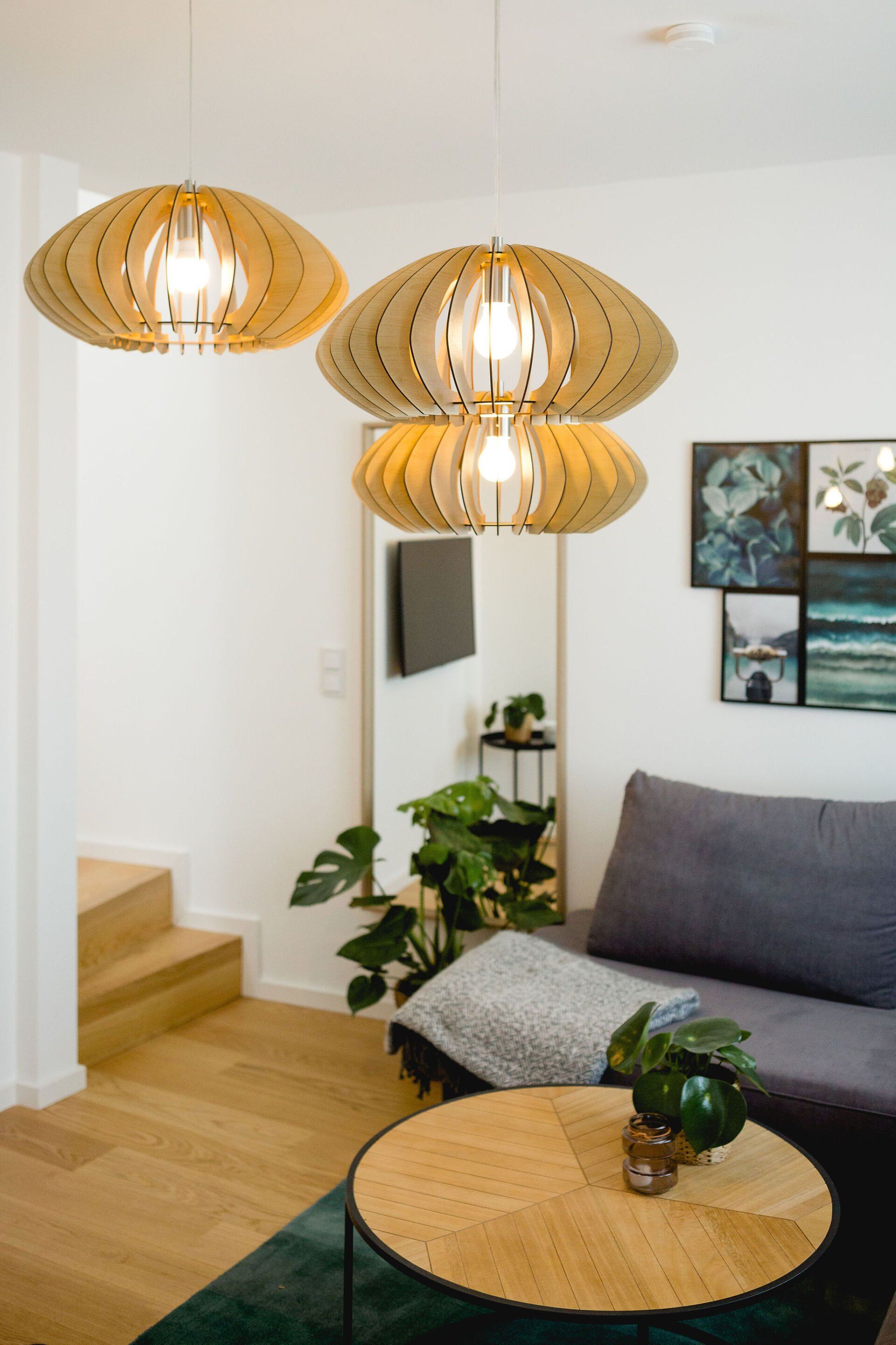 Ein Wohnzimmer mit Sofa, Couchtisch und von der Decke hängenden Lampen.