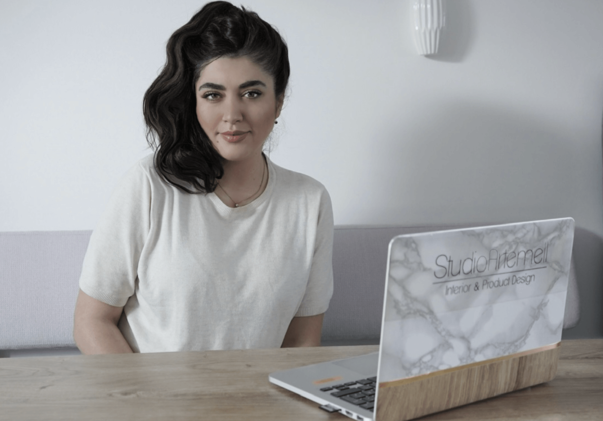Eine Frau sitzt an einem Tisch, auf dem ein Laptop steht.