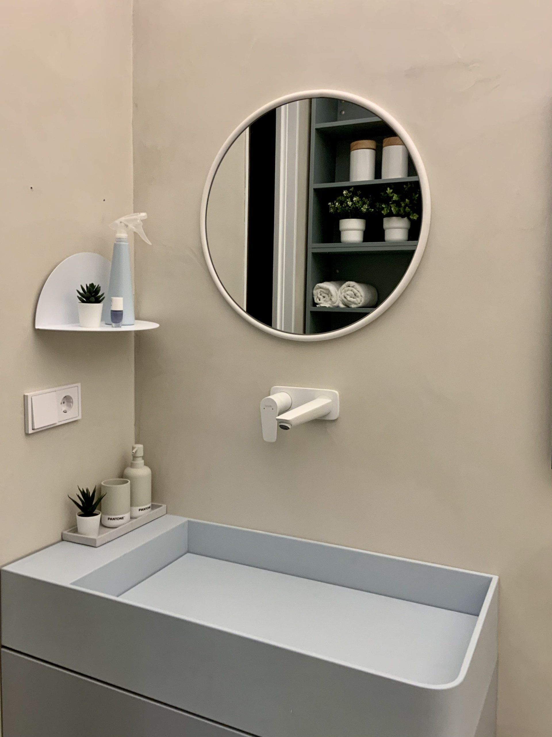 Ein Badezimmer mit Waschbecken und rundem Spiegel