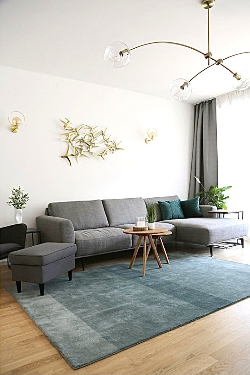 Ein Wohnzimmer mit Couch, Sessel, Tisch und Teppich.