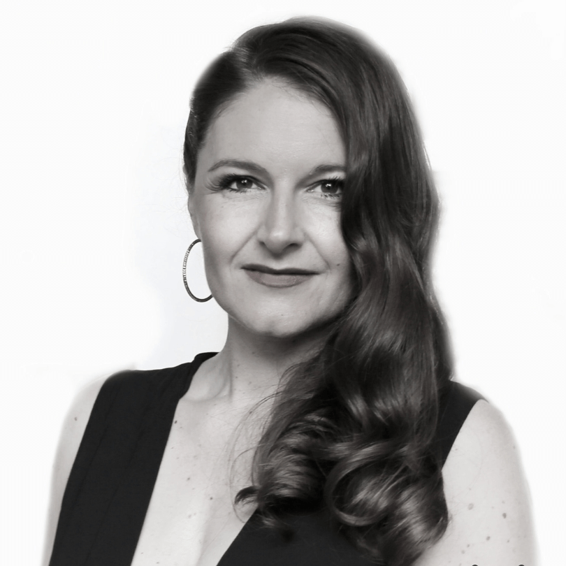 Eine Frau mit langen Haaren und Creolen lächelt auf einem Schwarzweißfoto.