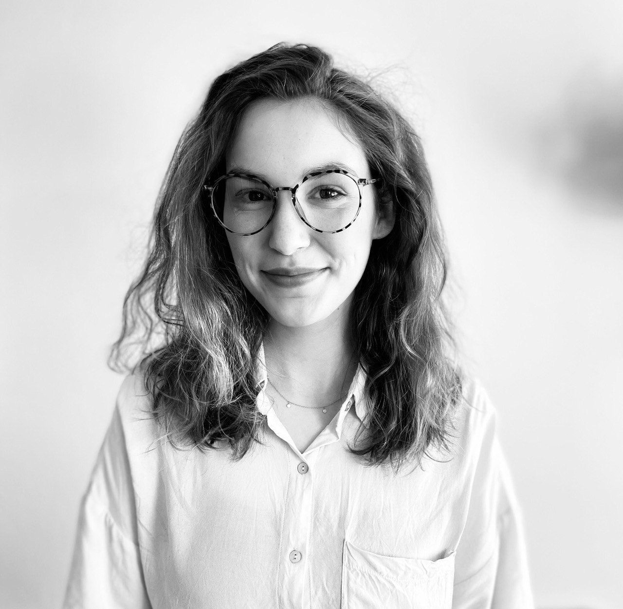 Ein Schwarzweißfoto einer Frau mit Brille und weißem Hemd.