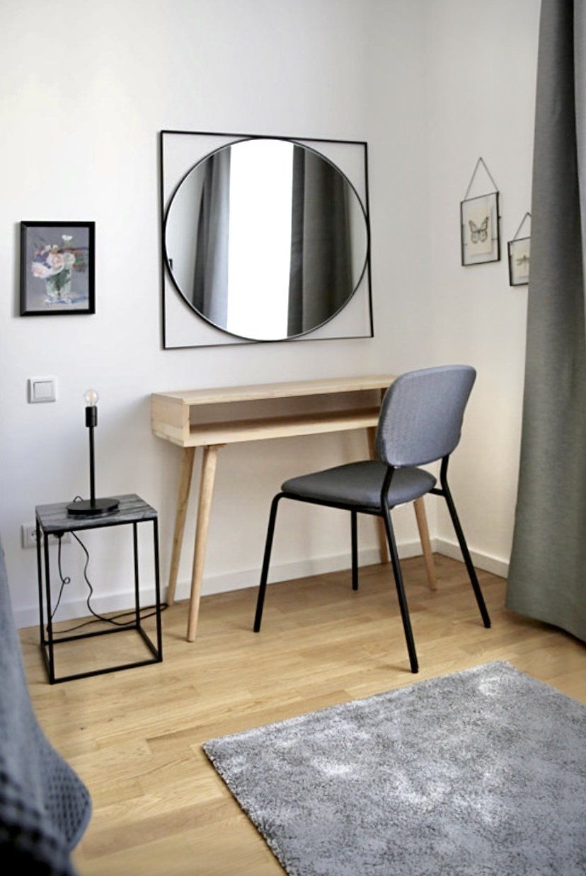 Ein Schlafzimmer mit Schreibtisch, Stuhl, Spiegel und Teppich.