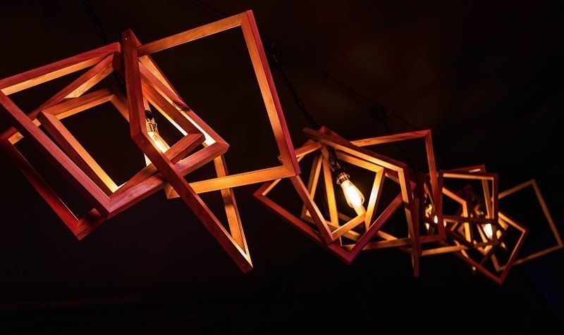 Eine Gruppe von Holzquadraten, die von der Decke hängen und in denen sich Lichter befinden.