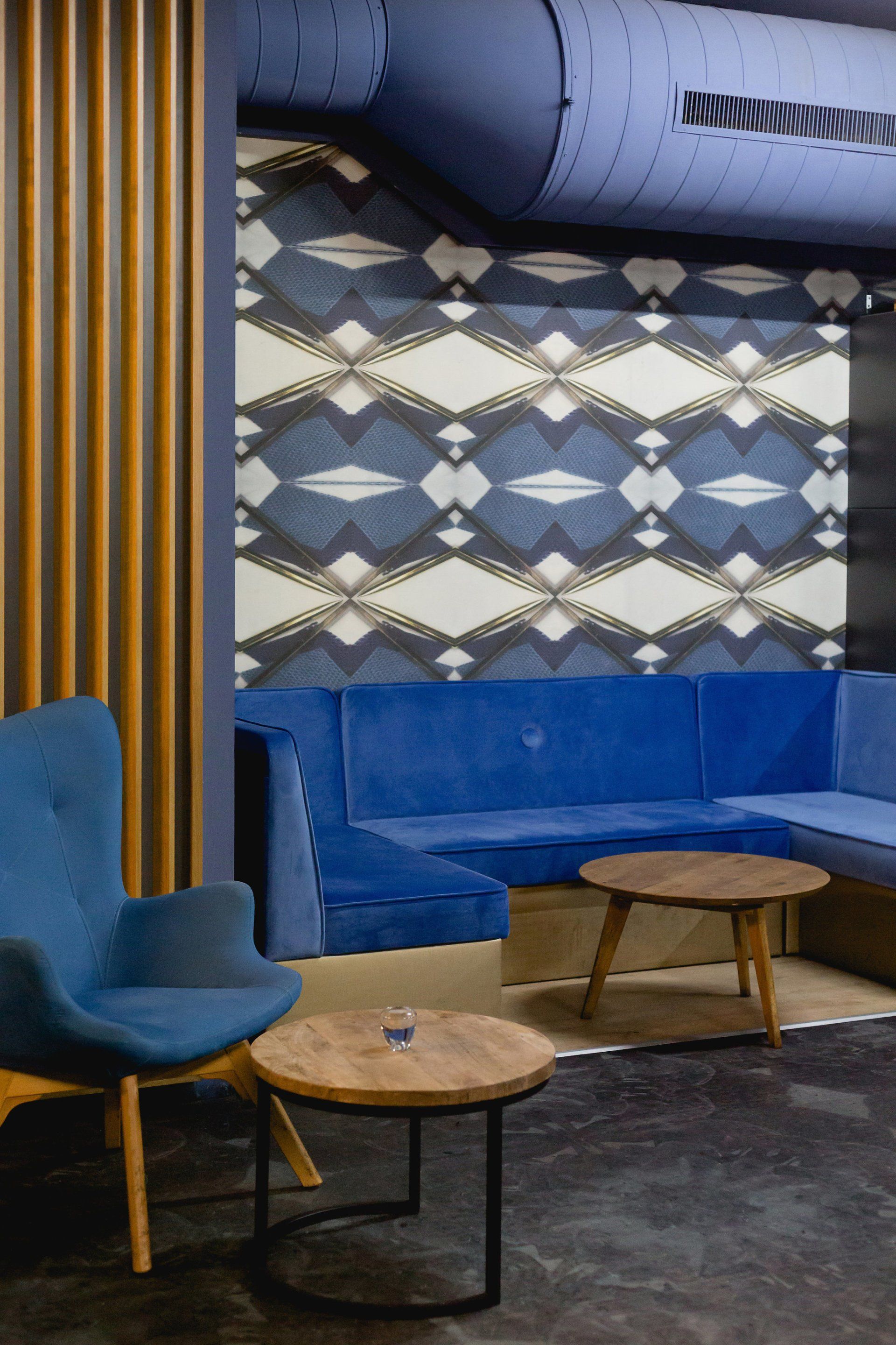 Ein Wohnzimmer mit einer blauen Couch, Stühlen und Tischen