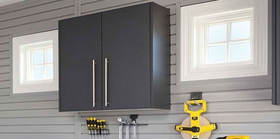 A garage with gray cabinets and two windows.
