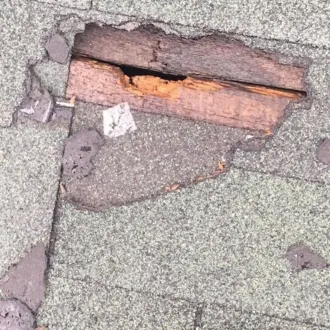 Leaking roof repair showing damaged shingles on a residential roof
