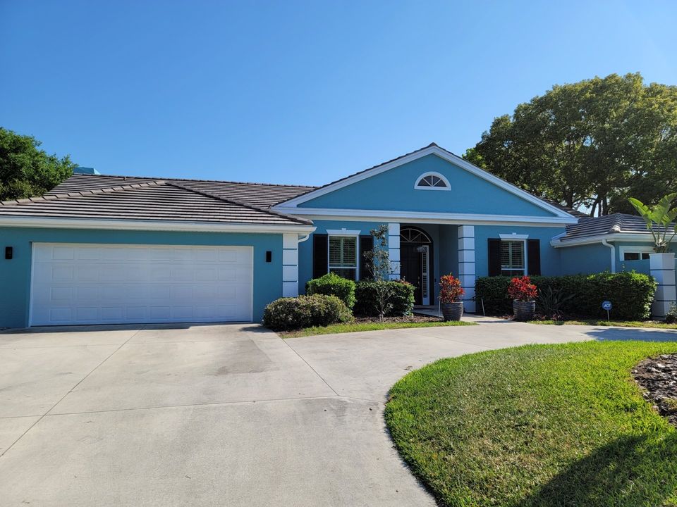 Image shows blue residential home with paved circular driveway and front lawn.