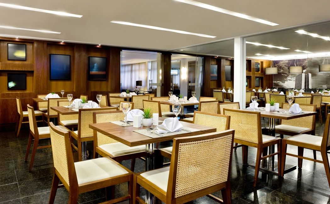 Um restaurante com mesas e cadeiras preparadas para o jantar