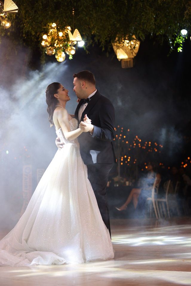 Newlyweds sharing a first dance at a softly lit wedding reception, stock example.