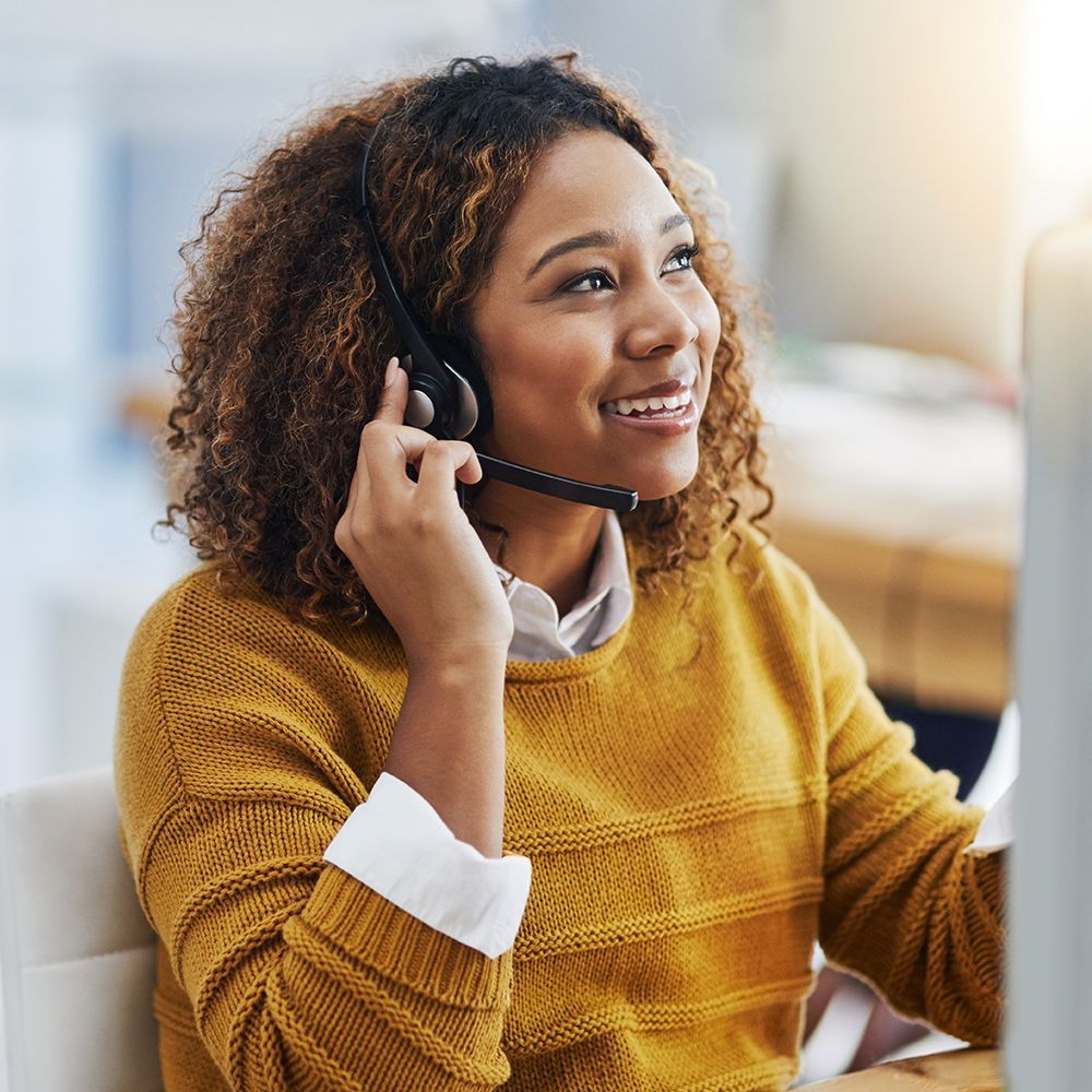 A woman wearing a headset is sitting in front of a computer.