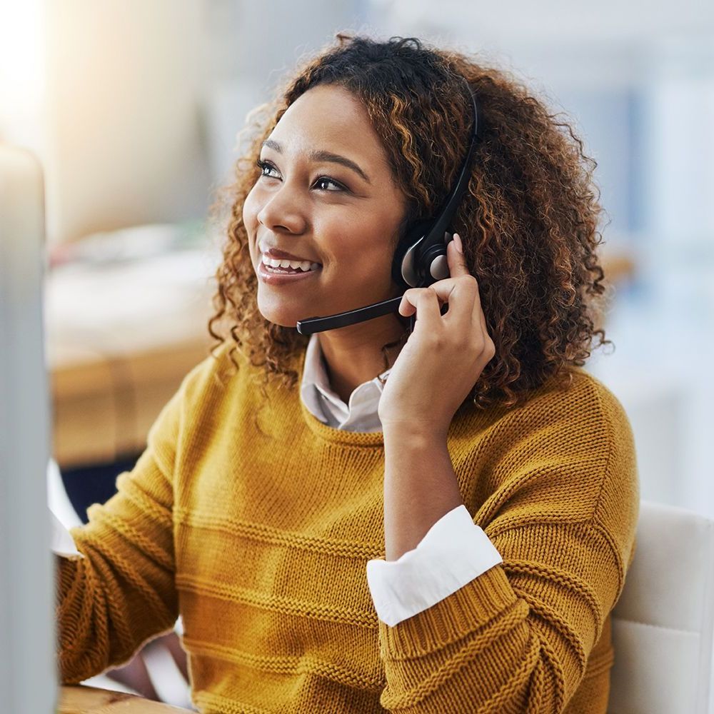 A woman wearing a headset is sitting in front of a computer.