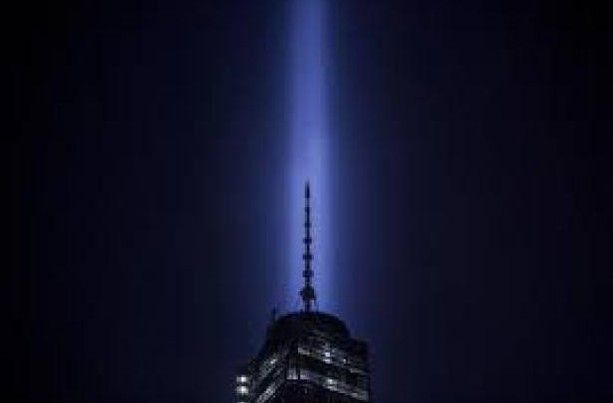 A tall building with a light coming out of it at night.