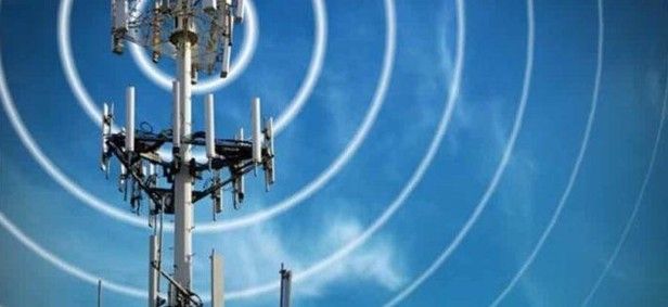 A cell phone tower with antennas against a blue sky.