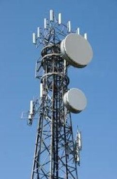 A telephone tower with a lot of antennas on it against a blue sky.