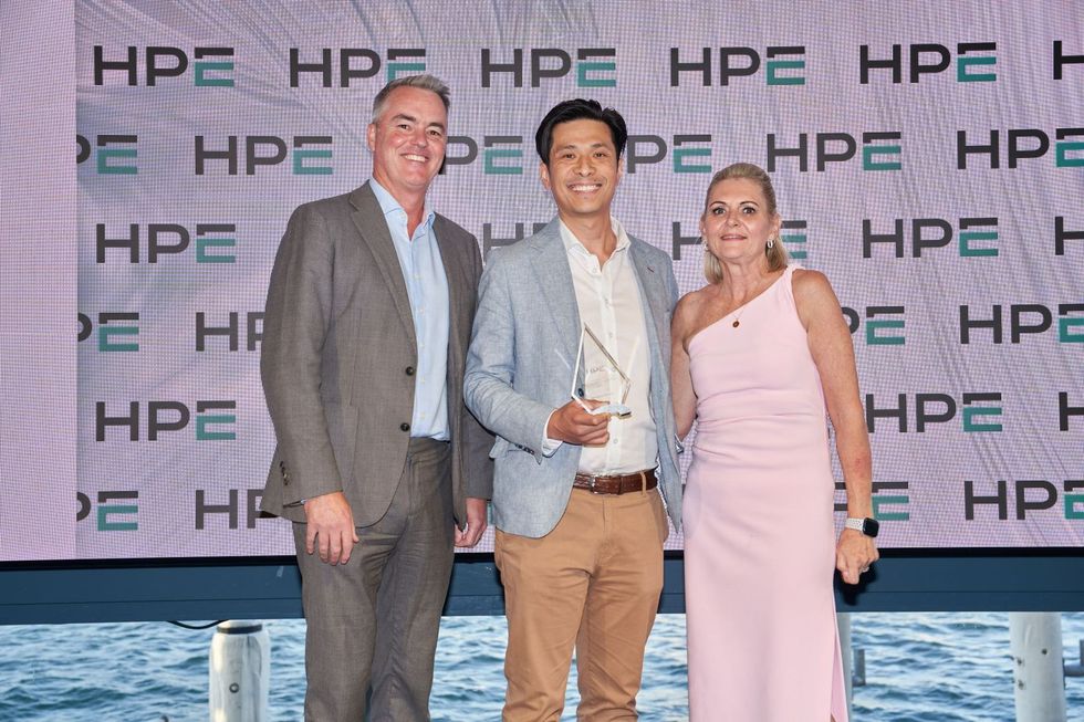 Three people posing for a photo at an HPE event, with an award.  Background has HPE logos.