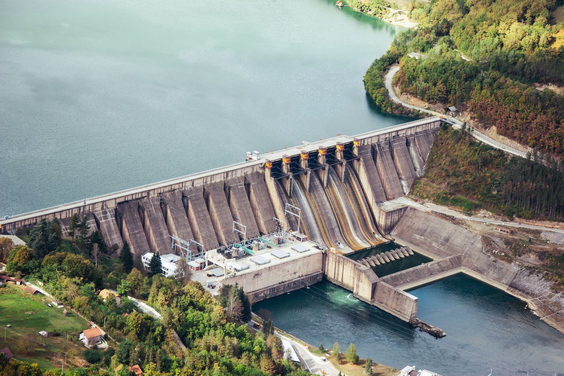 An aerial view of a large dam on a river surrounded by trees.
