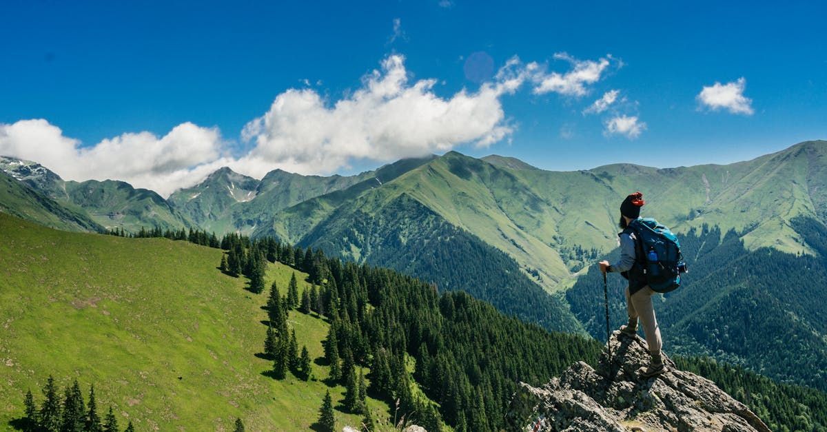 A person with a backpack is standing on top of a mountain.