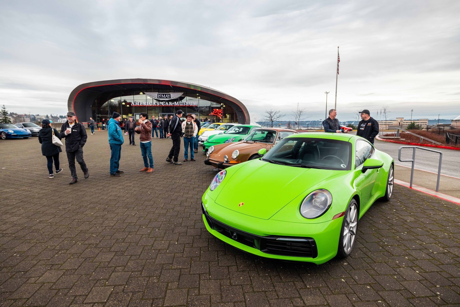 A group of people are standing around a green sports car.