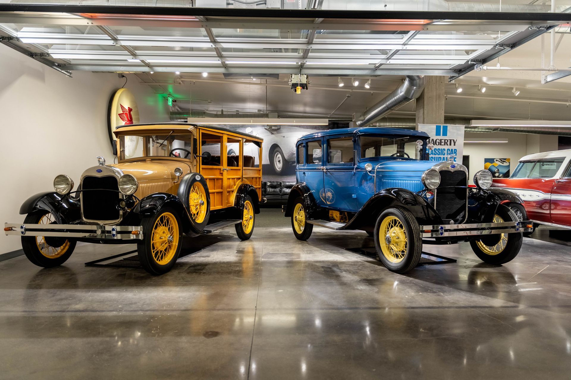 Three old cars are parked in a garage.