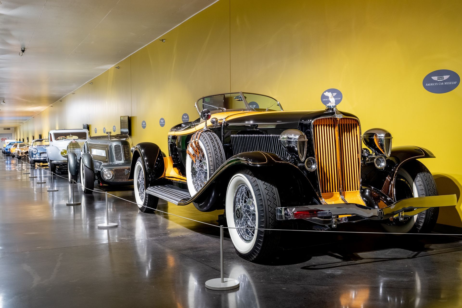 A row of old cars are on display in a museum.