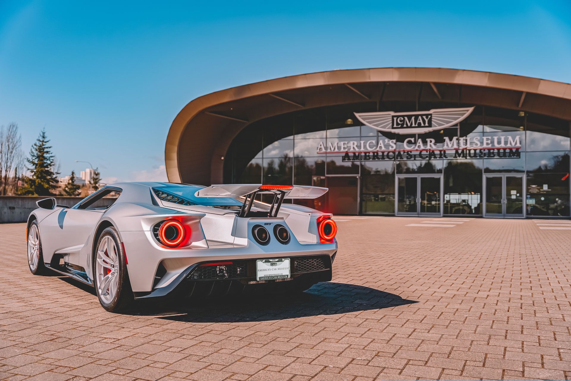 A silver sports car is parked in front of the american car museum.
