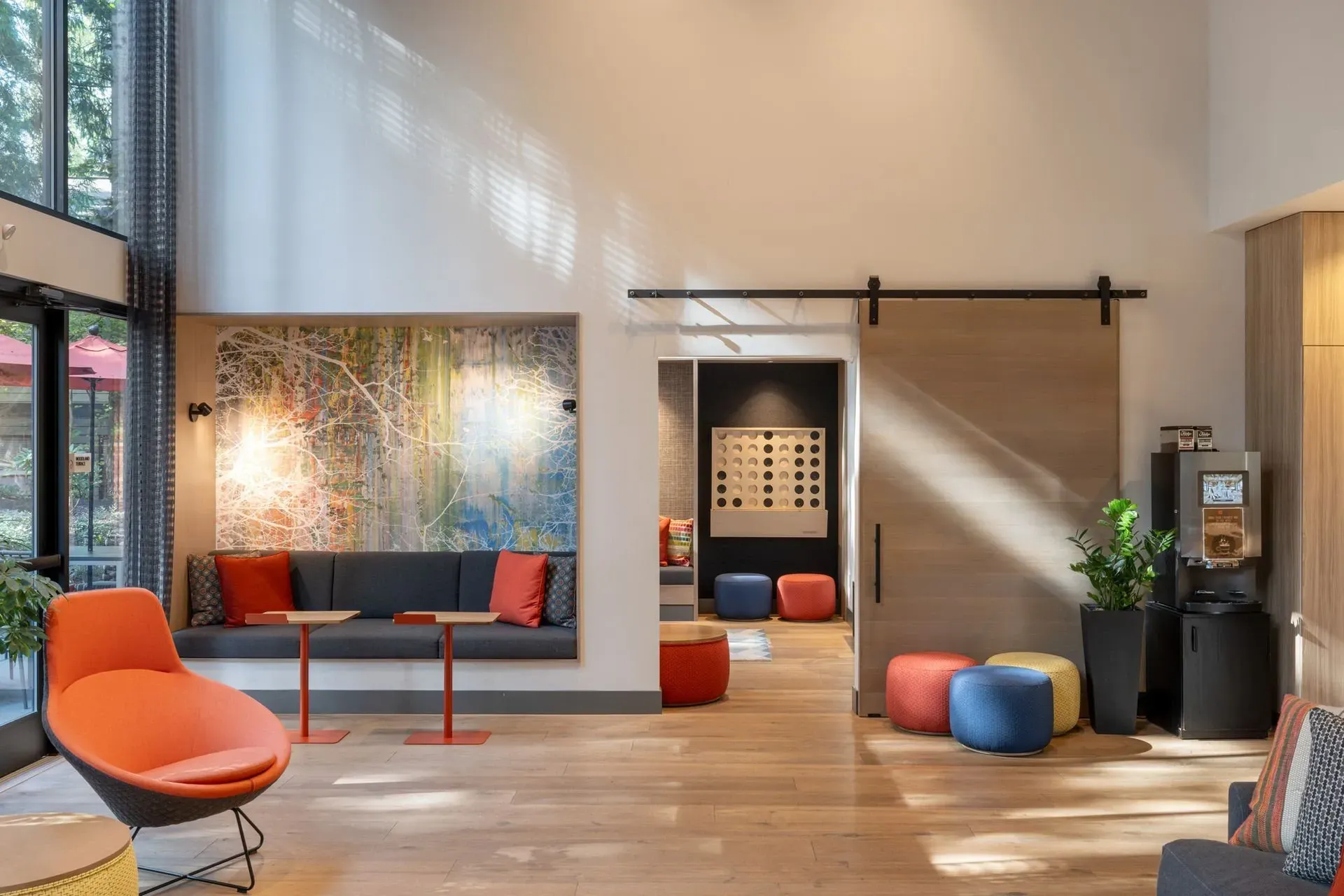 Modern apartment lobby with orange chair, built-in bench, sliding barn door, and abstract art at Park Bellevue apartment.