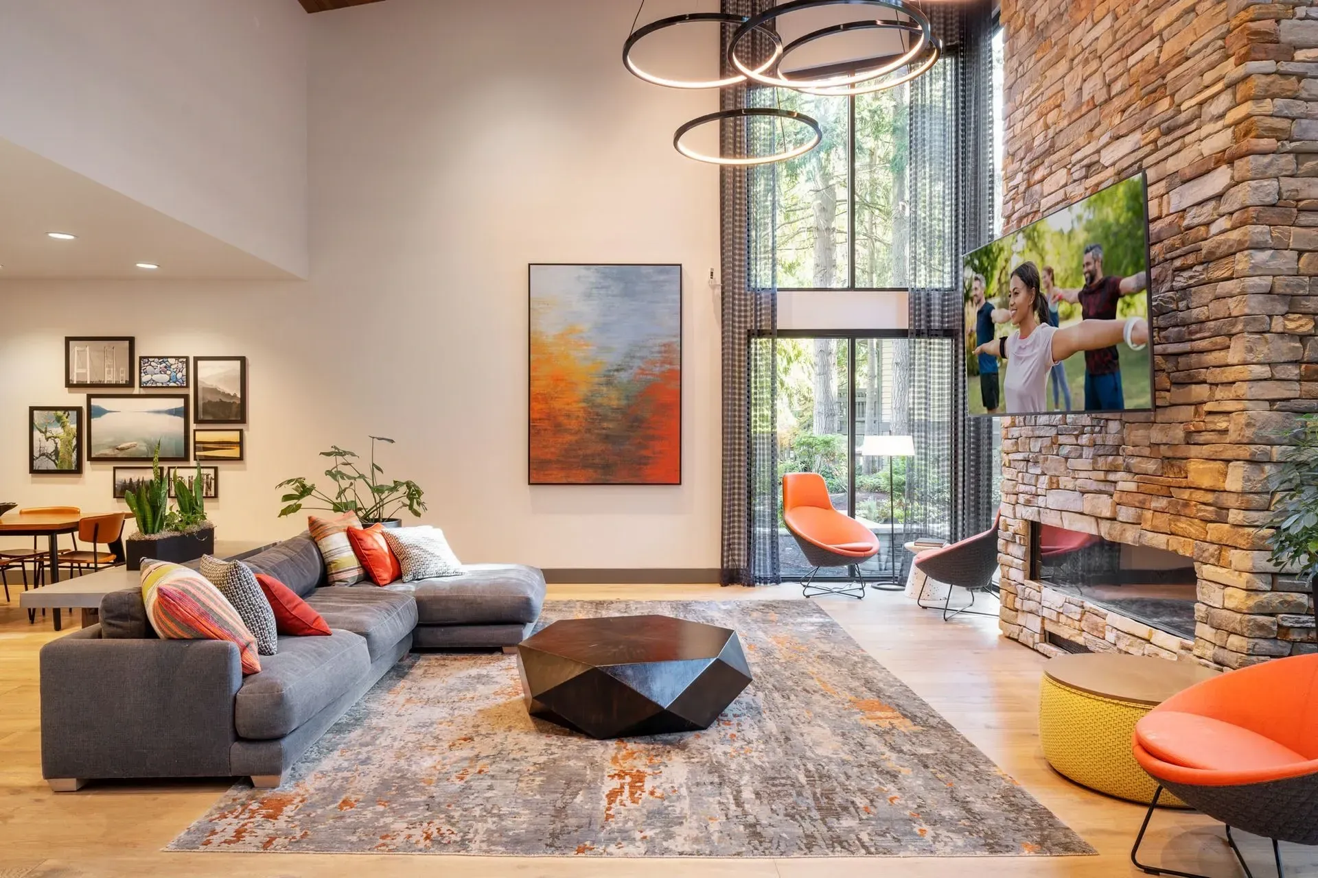 A modern clubhouse at Park Bellevue apartment community with a large sectional sofa, stone fireplace, art, and floor-to-ceiling windows.