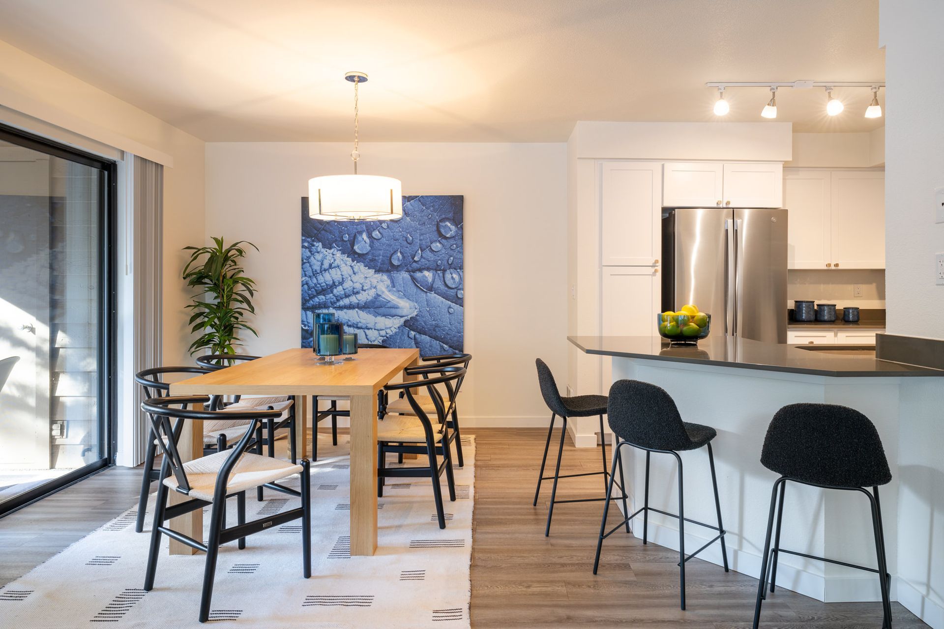 A dining room with a table and chairs and a kitchen with a refrigerator.