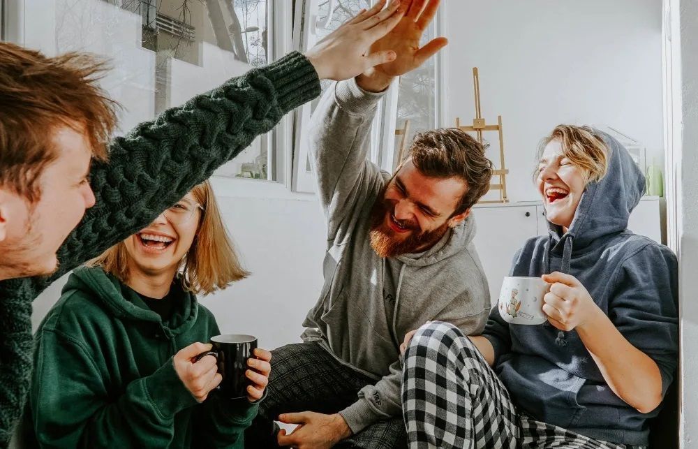 A group of people are sitting on the floor giving each other a high five.
