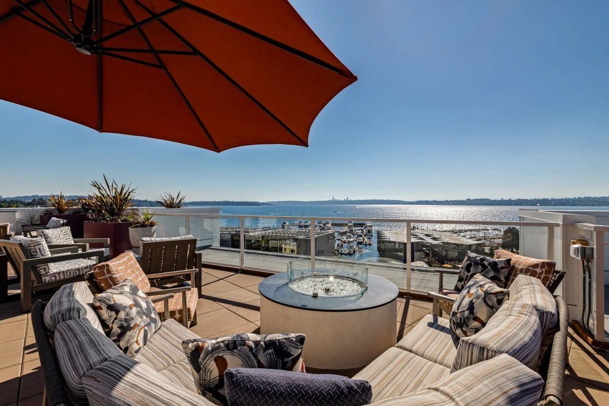 A patio with a fire pit and umbrellas overlooking the ocean.