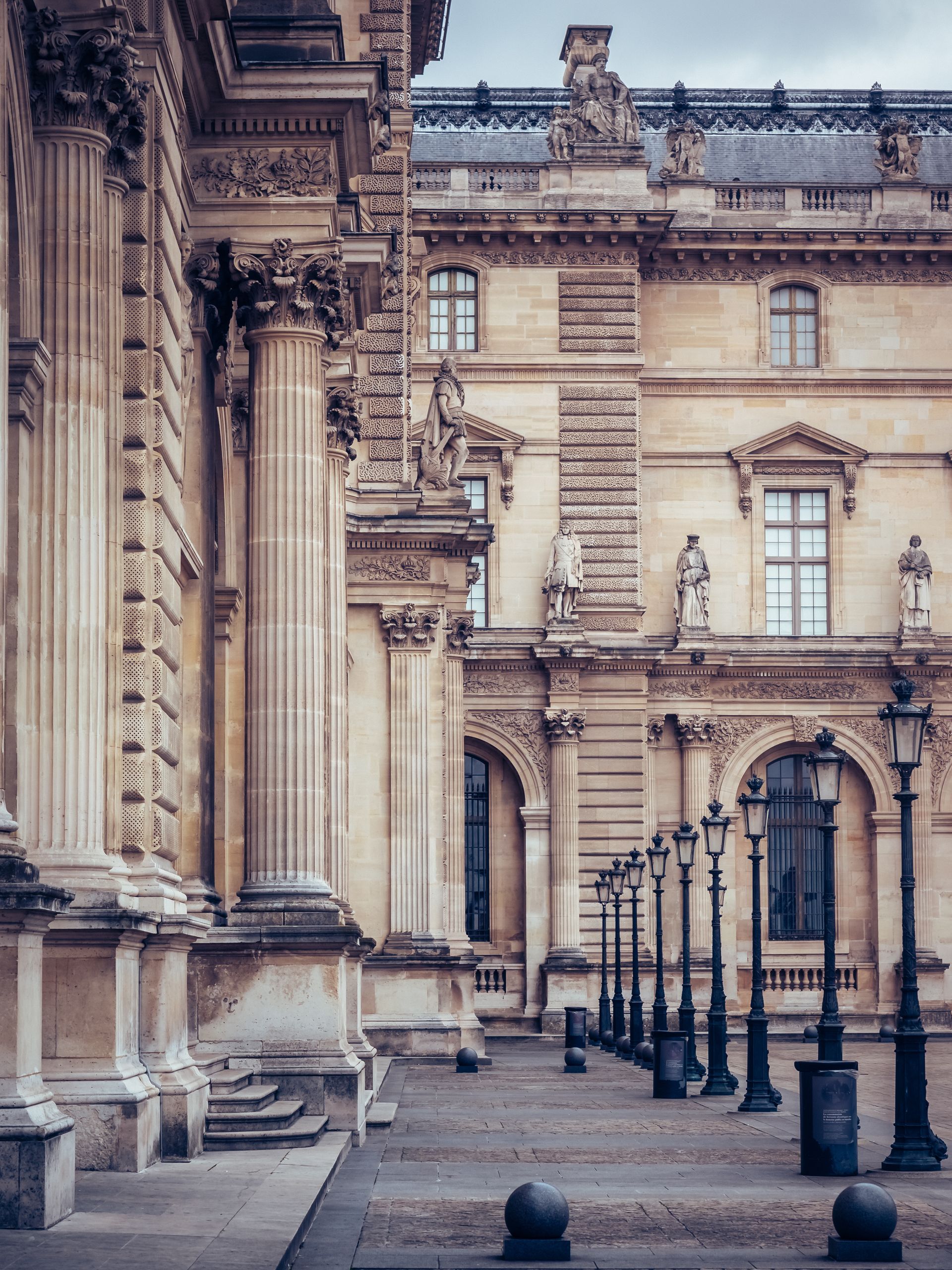 Une rangée de lampadaires est alignée devant un grand bâtiment.