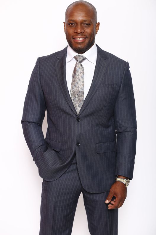 A man in a suit and tie is standing with his hands in his pockets.