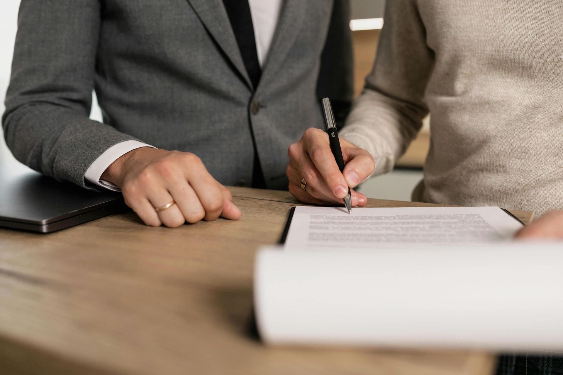 A man in a suit is writing on a clipboard with a pen.