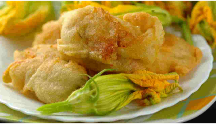 un piatto bianco condito con verdure e fiori fritti.