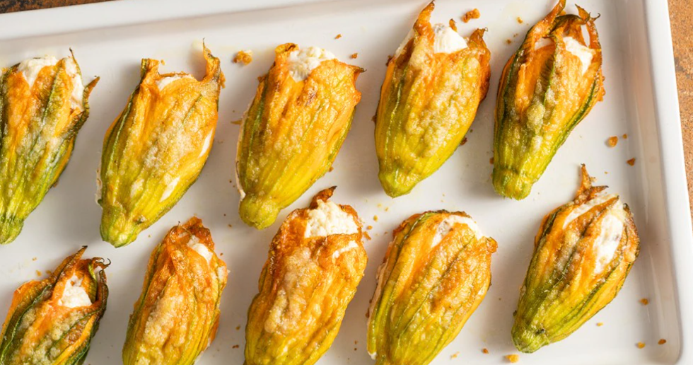 un vassoio bianco pieno di fiori di zucca ripieni.