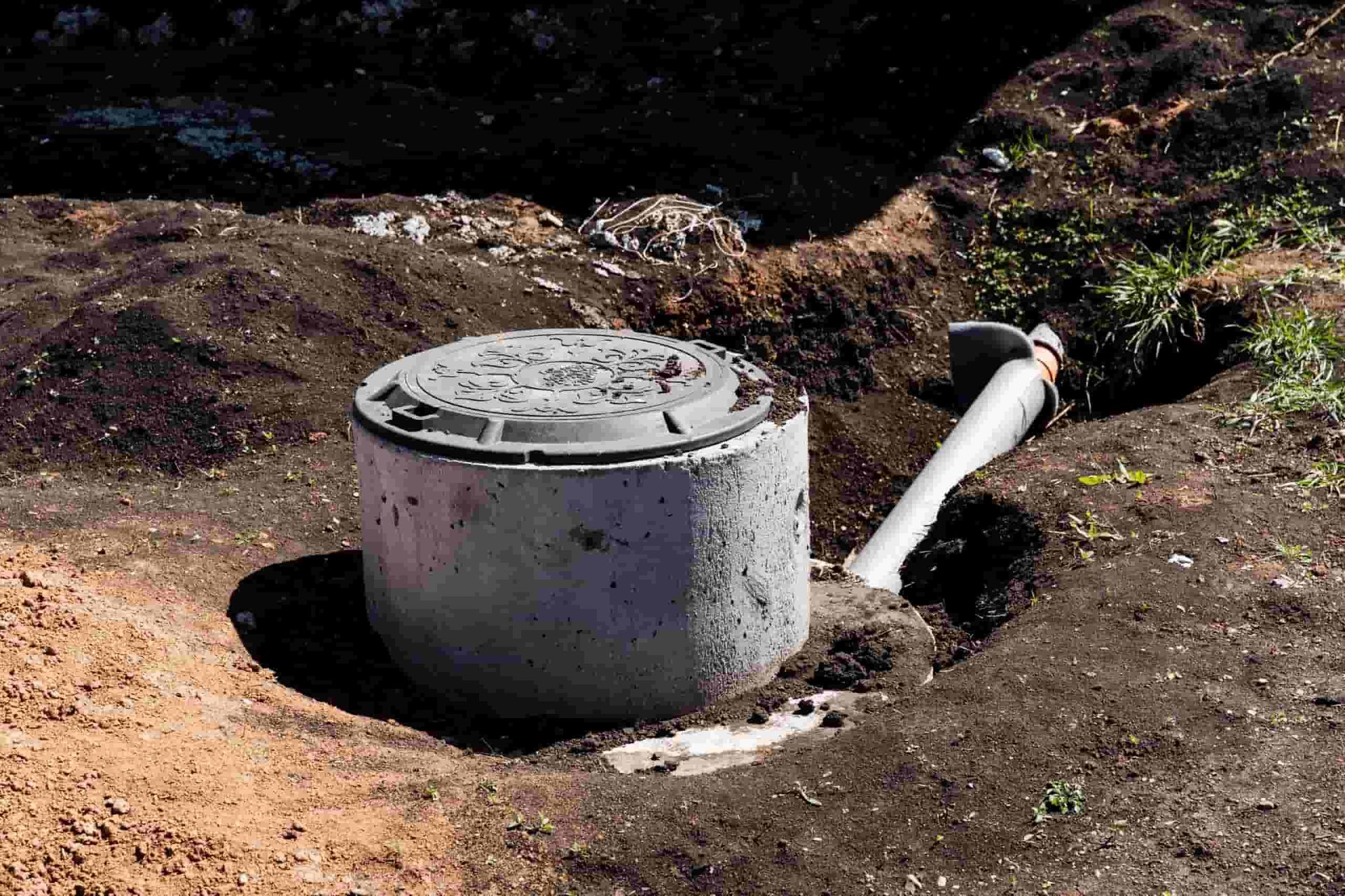 A Septic Tank is Sitting in the Dirt Next to a Pipe — Tony Gordon Septic Tank Cleaning in Bellingen, NSW