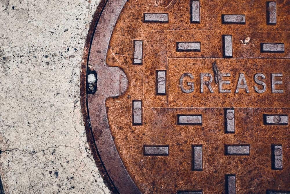 A Rusty Manhole Cover With the Word Grease Written on It — Tony Gordon Septic Tank Cleaning in Newee Creek, NSW