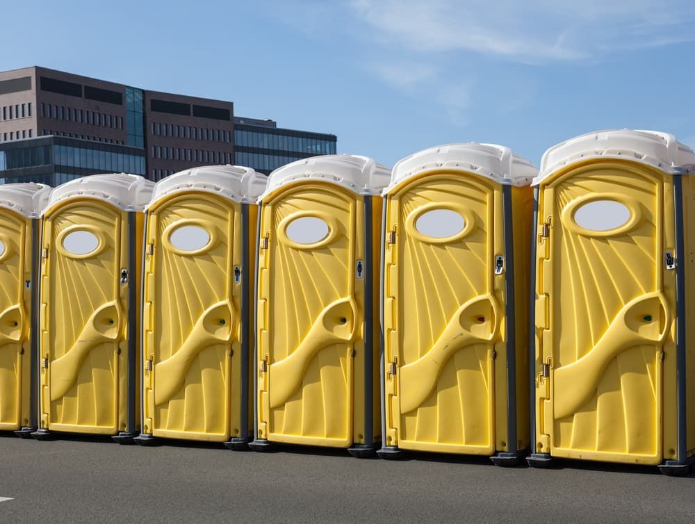 A Row of Yellow Portable Toilets Are Lined Up in a Parking Lot — Tony Gordon Septic Tank Cleaning in Nambucca Heads, NSW