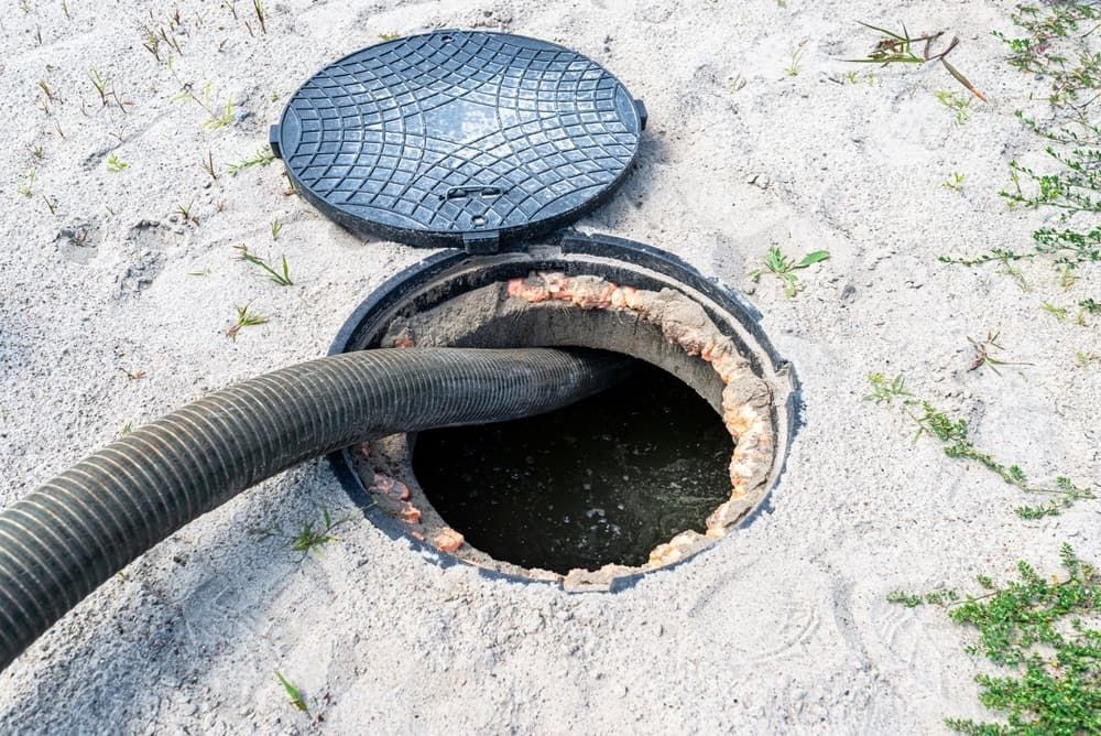 A Manhole Cover is Open and a Hose is Coming Out of It — Tony Gordon Septic Tank Cleaning in Bellingen, NSW