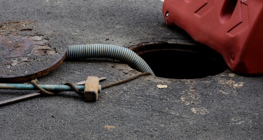 A Manhole Cover With a Hose Coming Out of It — Tony Gordon Septic Tank Cleaning in Newee Creek, NSW