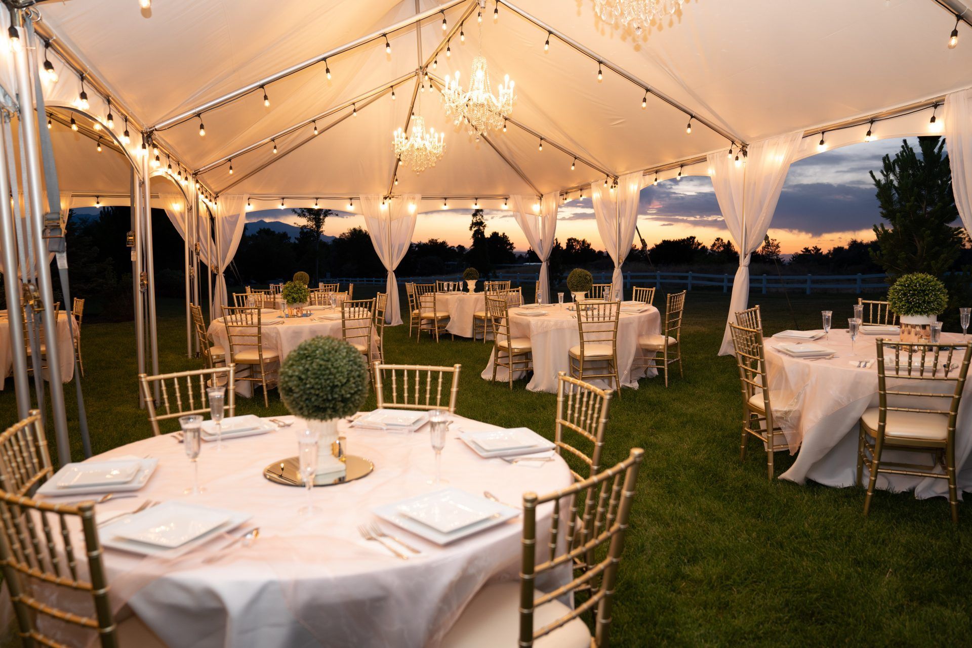 Memorial Mortuaries Celebration of life tent set up with tables, chairs and flowers at night with lights on