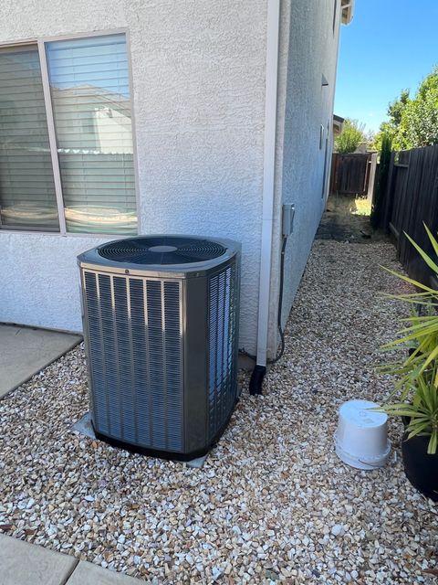 An air conditioner is sitting on the side of a house next to a window.